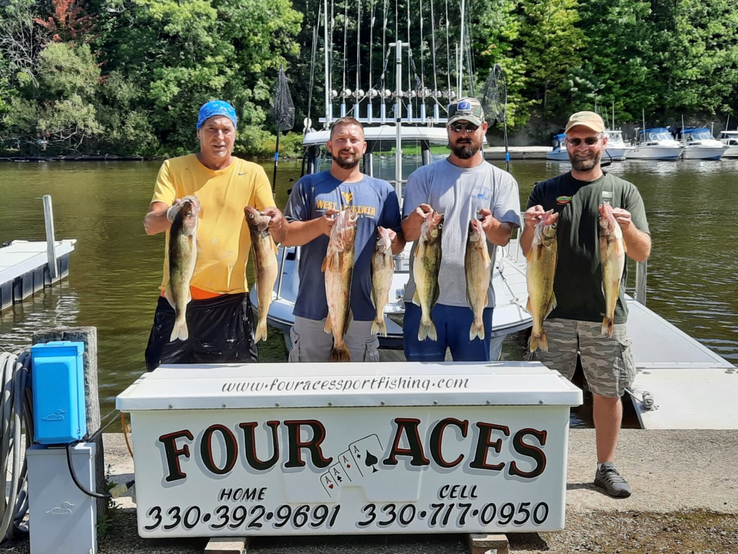 Four men holding pairs of fish